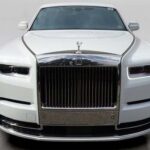 A white Rolls-Royce luxury car featuring a sleek front design and a prominent chrome grille, against a neutral background.