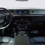 Luxurious interior of a Rolls-Royce, showcasing a sleek dashboard, elegant controls, and premium leather upholstery.