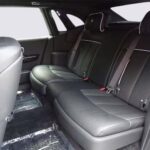 Luxurious black leather interior of a car's backseat, featuring spacious seating, seat belts, and elegant detailing.